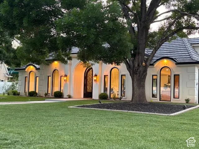 View of front facade with stucco siding and a front yard