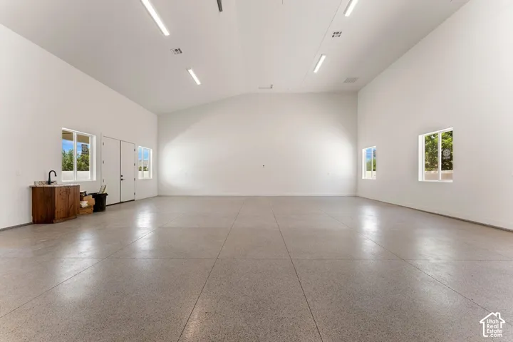 Spare room featuring vaulted ceiling and dark aggregate flooring