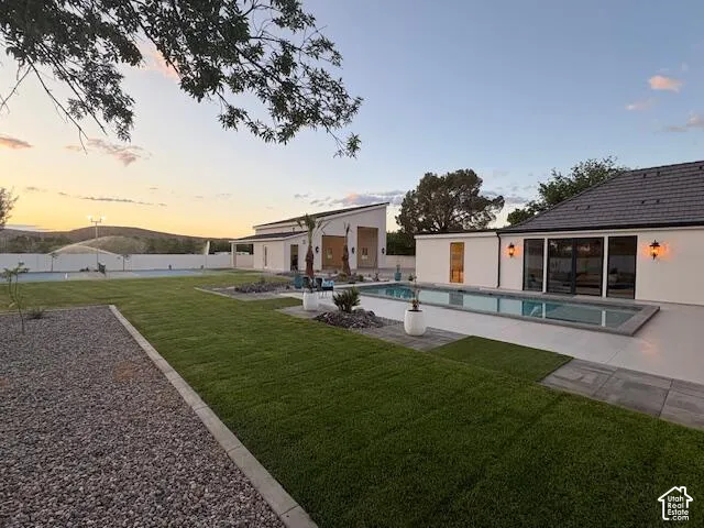 Back of house at dusk with a patio and a yard