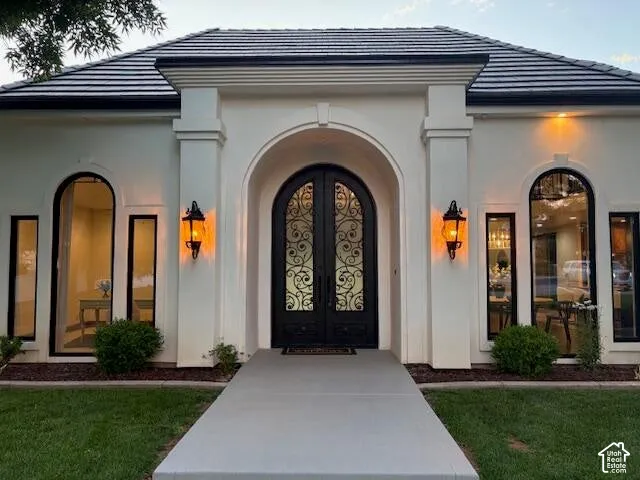 View of exterior entry featuring a tile roof, french doors, and stucco siding