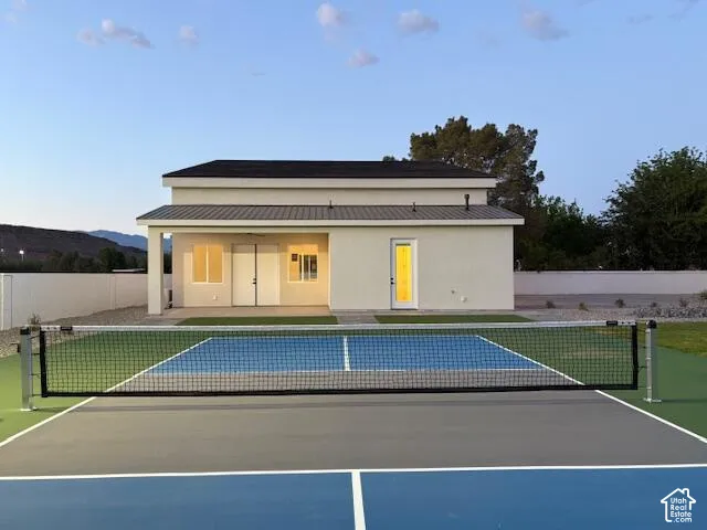 Back of house at dusk with a sport court, a patio, and stucco siding
