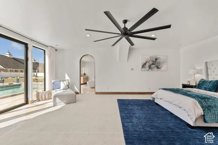 Primary Owner Suite with access to outside, ceiling fan, arched walkways, and recessed lighting