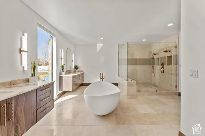 Primary Owner Bathroom featuring a stall shower, two vanities, a soaking tub, and recessed lighting