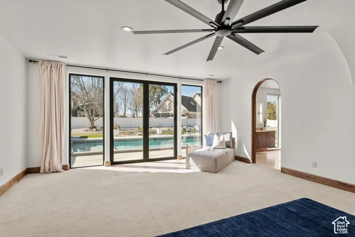 Primary Owner Suite with light carpet, ceiling fan, recessed lighting, and arched walkways