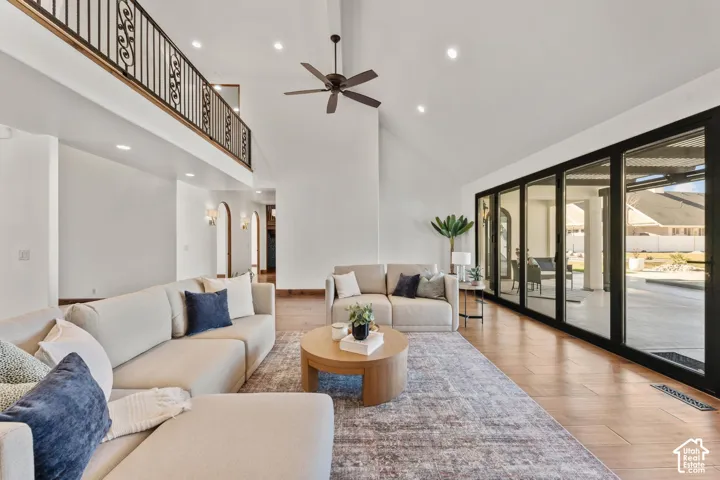Living room with wood finished floors, recessed lighting, ceiling fan, sliding panel doors and vaulted ceiling