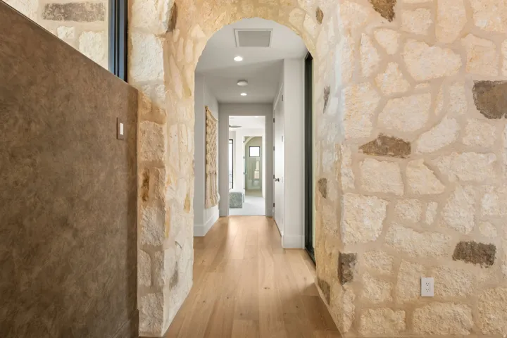 Hallway featuring arched walkways, light wood-type flooring, and recessed lighting