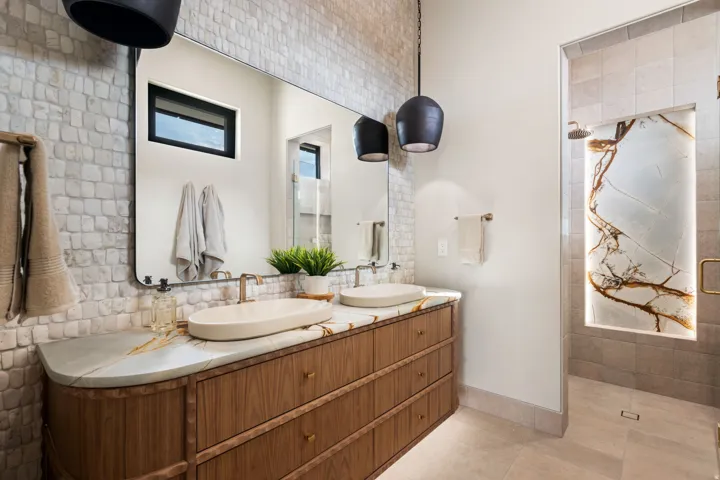 Bathroom with tiled shower, double vanity, and light tile patterned floors