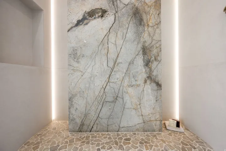 Full bathroom with stone flooring and a marble finish shower