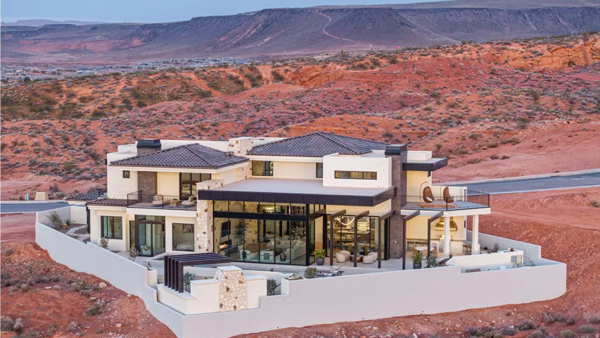 Back of property featuring a patio area, a mountain view, a balcony, stucco siding, and stone siding