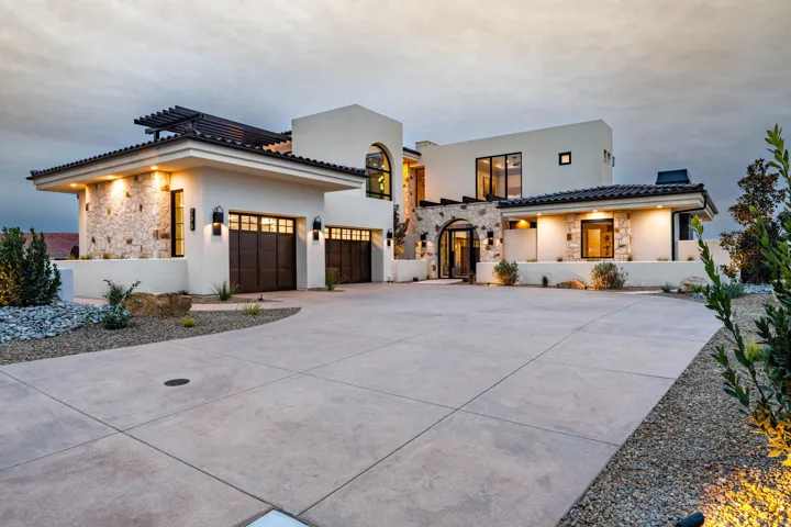 View of front facade with stone siding, concrete driveway, stucco siding, and an attached garage