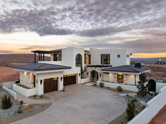 View of front of property with stone siding, driveway, stucco siding, a garage, and a tile roof