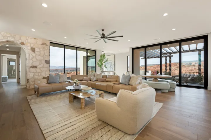 Living room with floor to ceiling windows, a mountain view, arched walkways, hardwood / wood-style floors, and a ceiling fan