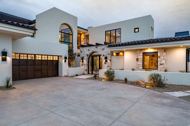 View of front of home featuring driveway, stone siding, and stucco siding
