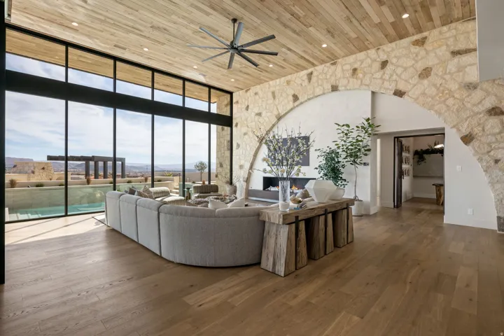 Living area featuring a high wood ceiling, floor to ceiling windows, hardwood / wood-style floors, ceiling fan, and a warm lit fireplace