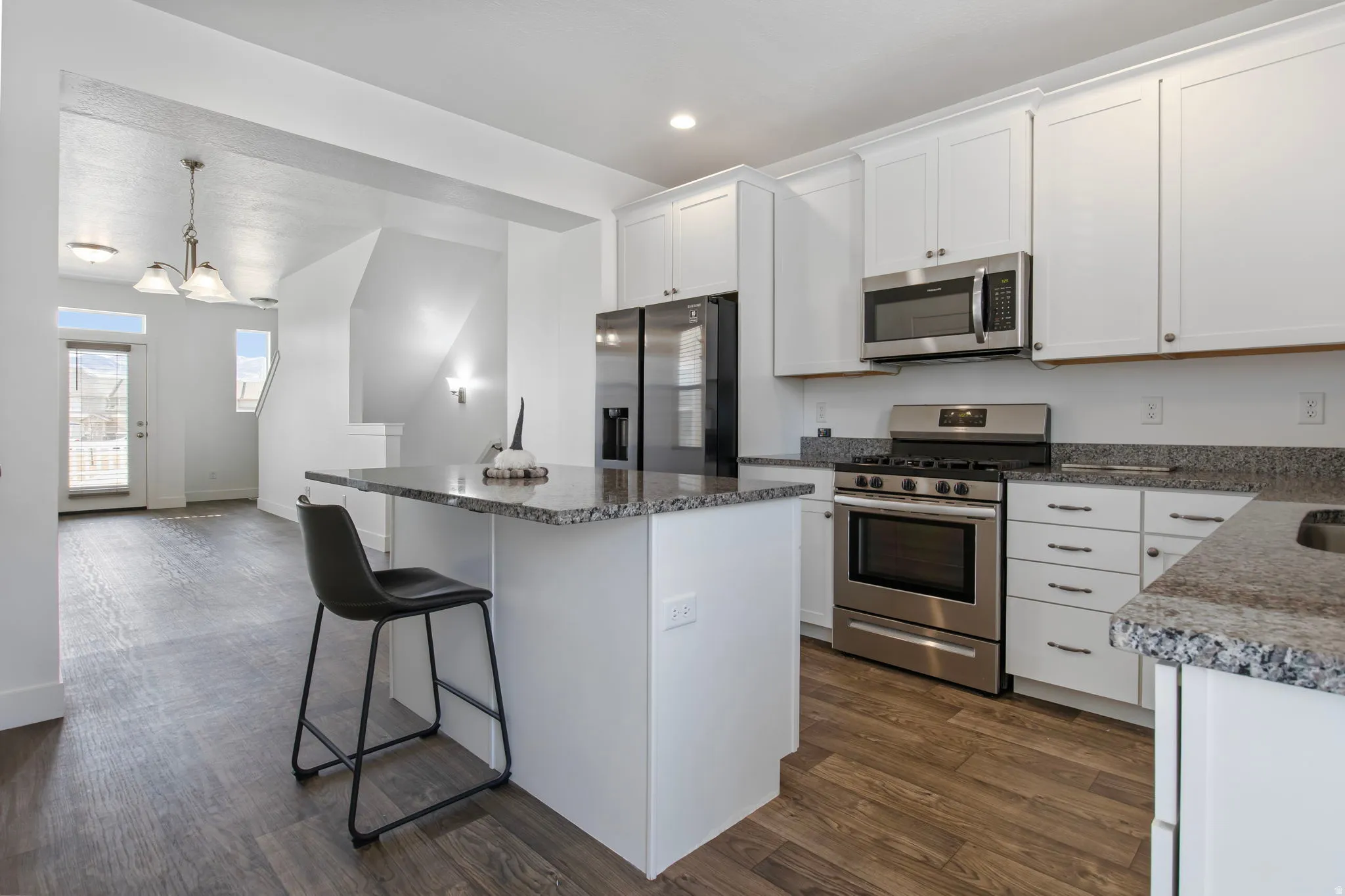 Kitchen featuring a breakfast bar, stainless steel appliances, white cabinets, a center island, and dark wood finished floors