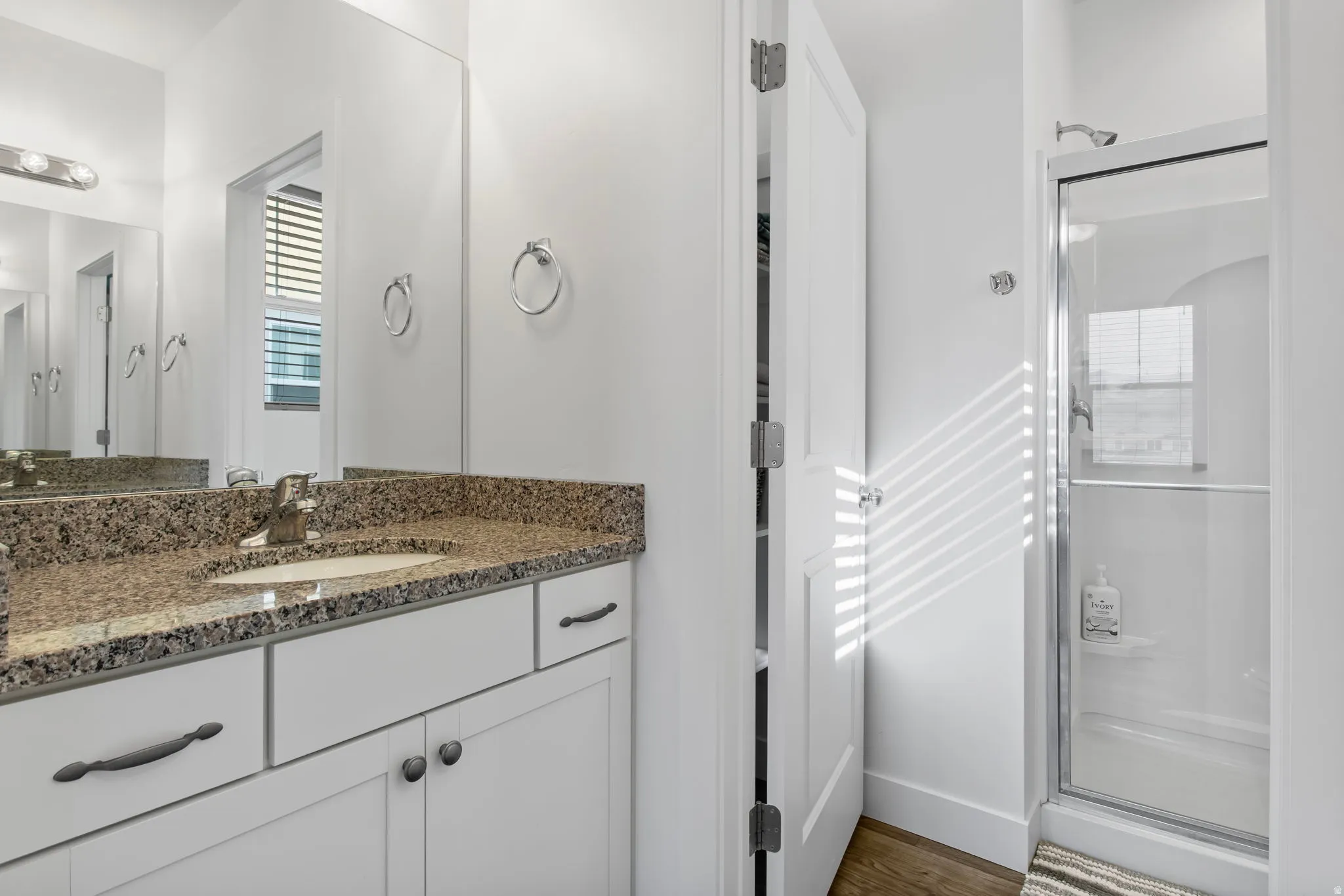 Full bath featuring a shower stall, vanity, and dark wood-style flooring