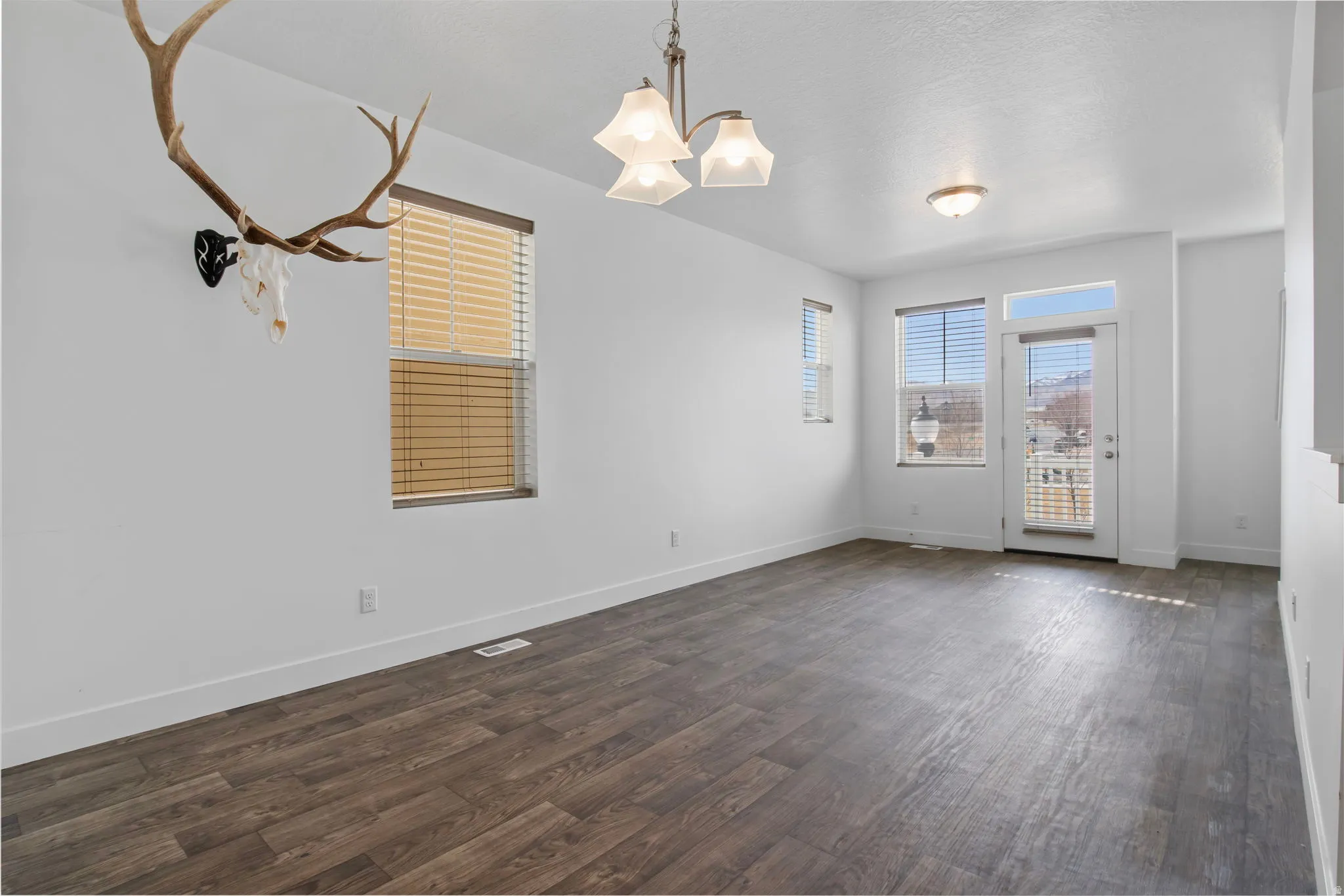 Unfurnished dining area with suspended lighting and dark wood finished floors