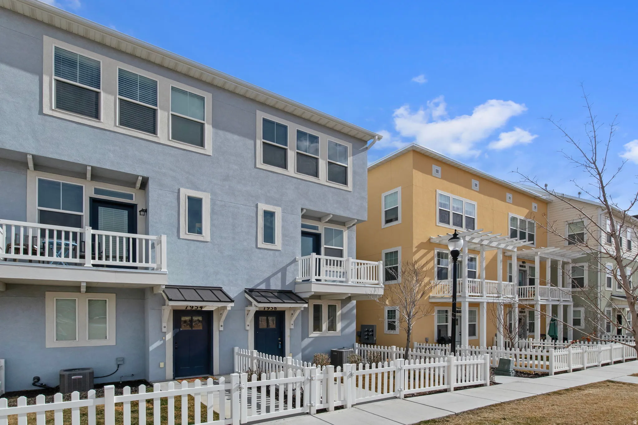 View of front facade featuring stucco siding, a balcony, a standing seam roof, and a fenced front yard
