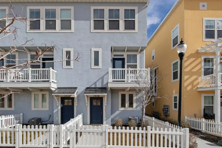 Traditional home with a standing seam roof, stucco siding, a balcony, a fenced front yard, and a gate