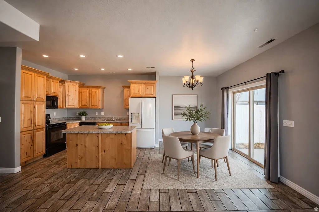 Open-concept living space featuring wood-finish flooring, a kitchen island with stone-look countertops, and ample cabinetry
