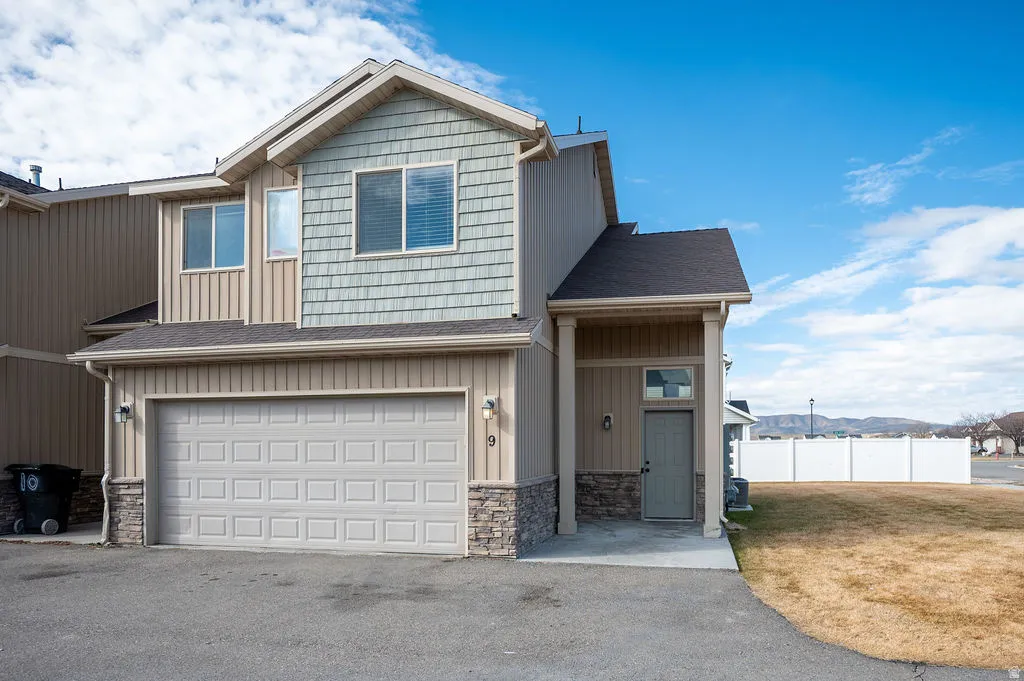 View of front of property with a garage, a shingled roof, asphalt driveway, and board and batten siding