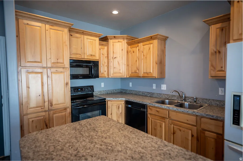 Kitchen with black appliances, light wood finish cabinetry, recessed lighting, and dark stone counters