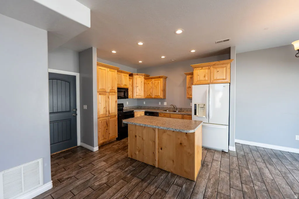 Kitchen with black appliances, a center island, wood tiled floors, recessed lighting, and light wood finish cabinetry