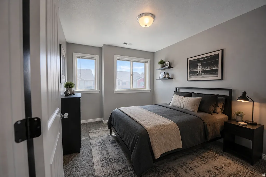 Bedroom featuring two windows, neutral wall tones, textured carpeting, and a flush-mount ceiling light fixture