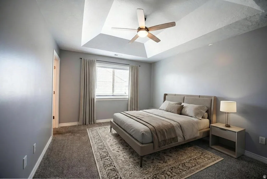 Bedroom with carpet floors, a ceiling fan, and a tray ceiling