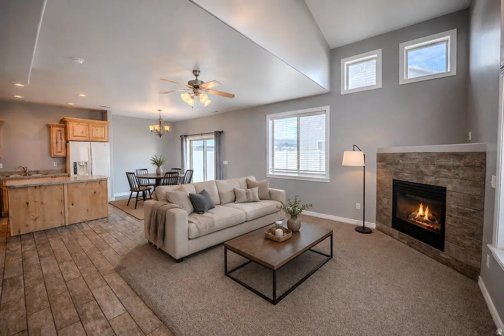 Great room featuring a fireplace with stone surround, vaulted ceilings, and multiple windows