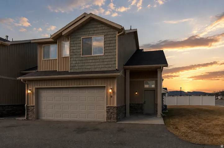 Two-story residence featuring a two-car garage with overhead door and an exterior combining horizontal siding, shake siding, and stone accents