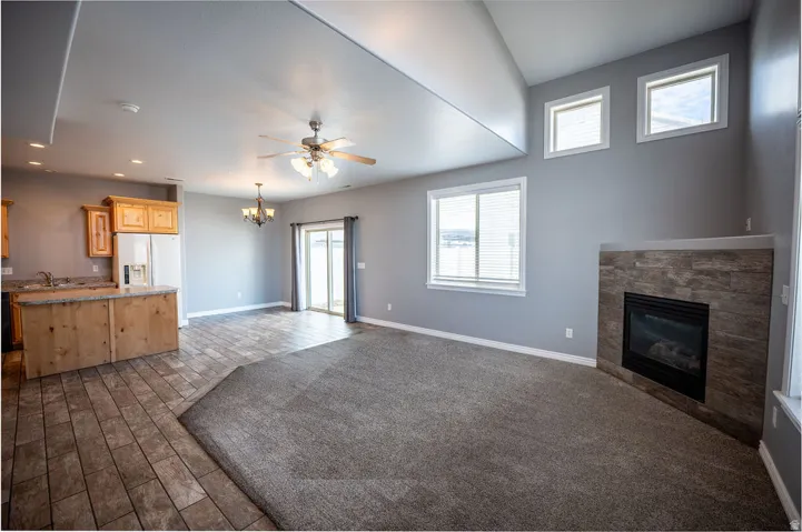 Unfurnished living room featuring a chandelier, a glass covered fireplace, a ceiling fan, and wood finish floors
