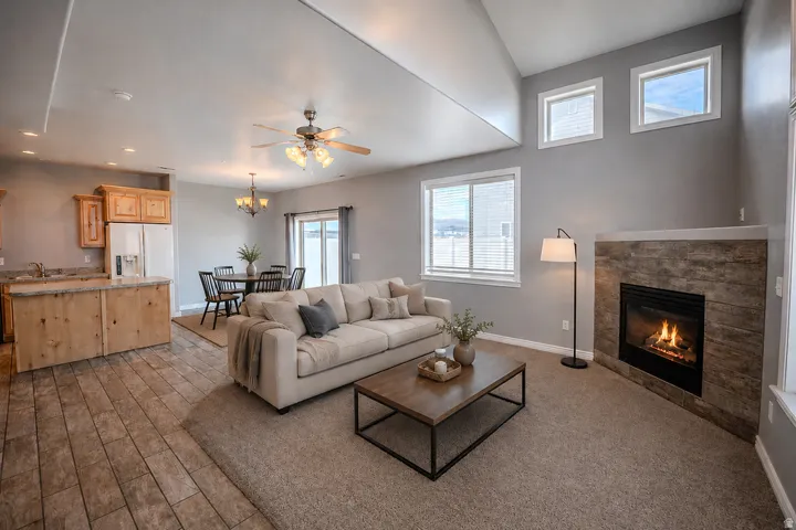 Great room featuring a fireplace with stone surround, vaulted ceilings, and multiple windows