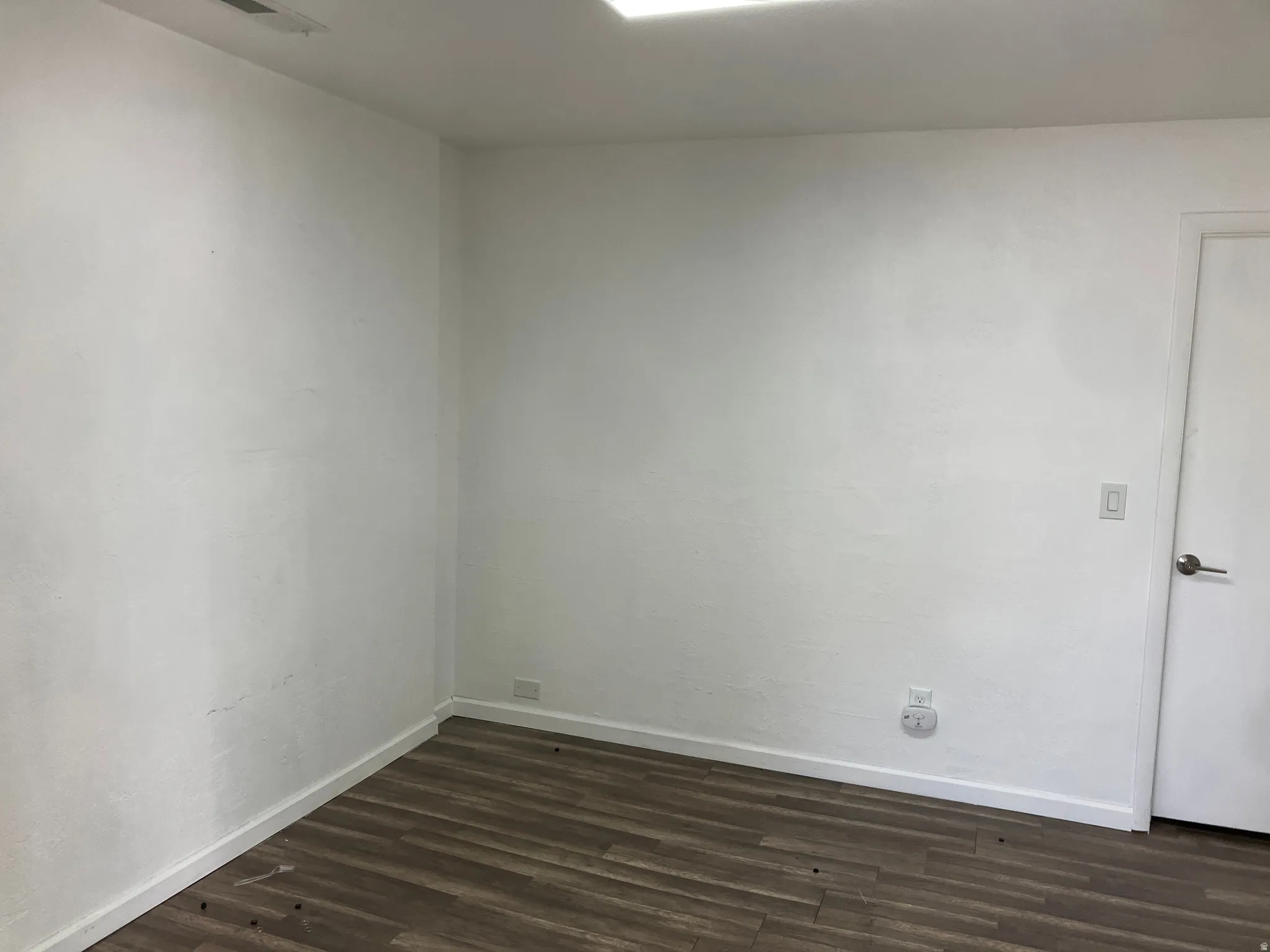 Empty room featuring baseboards and dark wood-style flooring