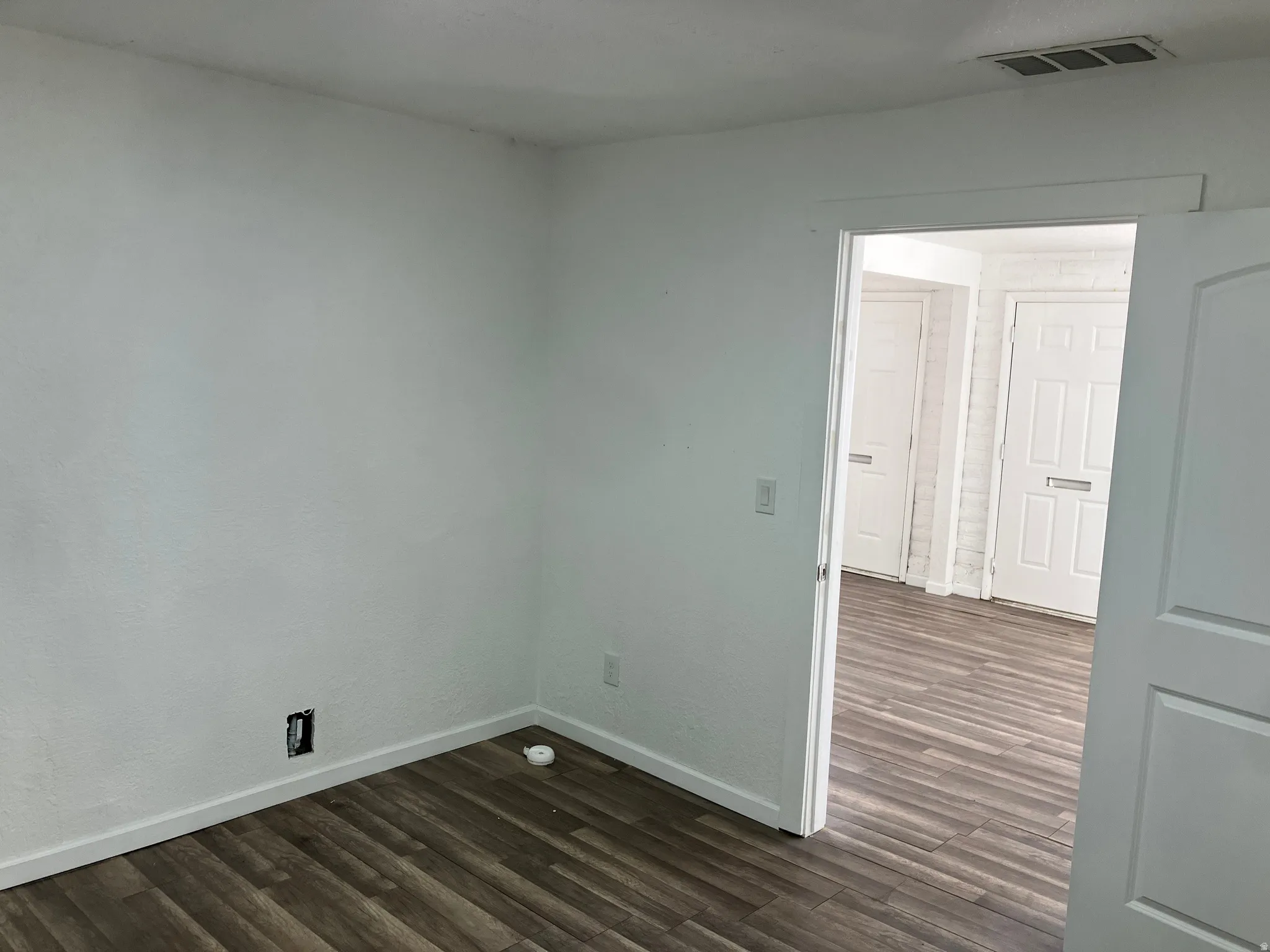 Spare room with dark wood-style flooring and baseboards