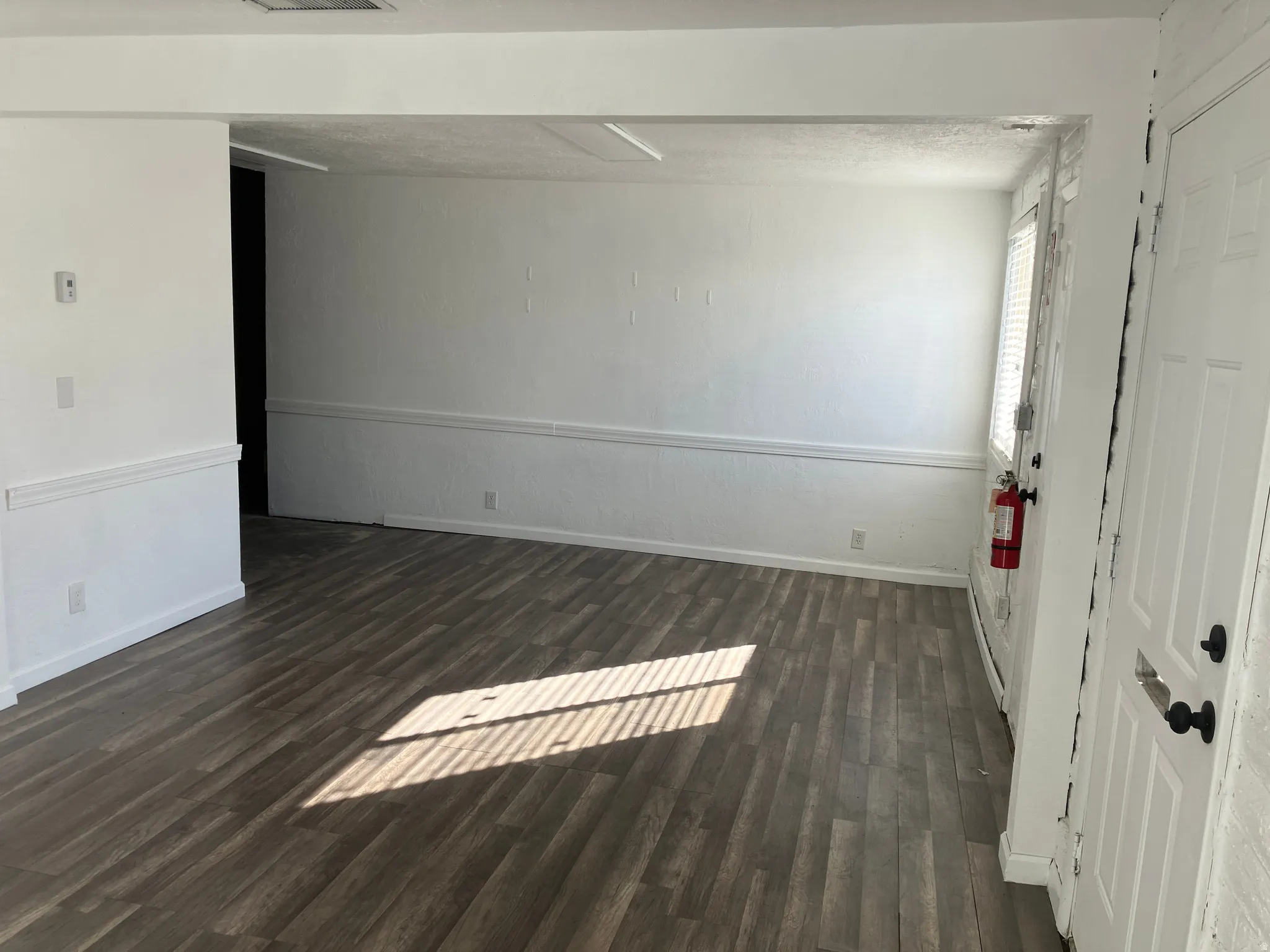Empty room featuring dark wood finished floors and baseboards