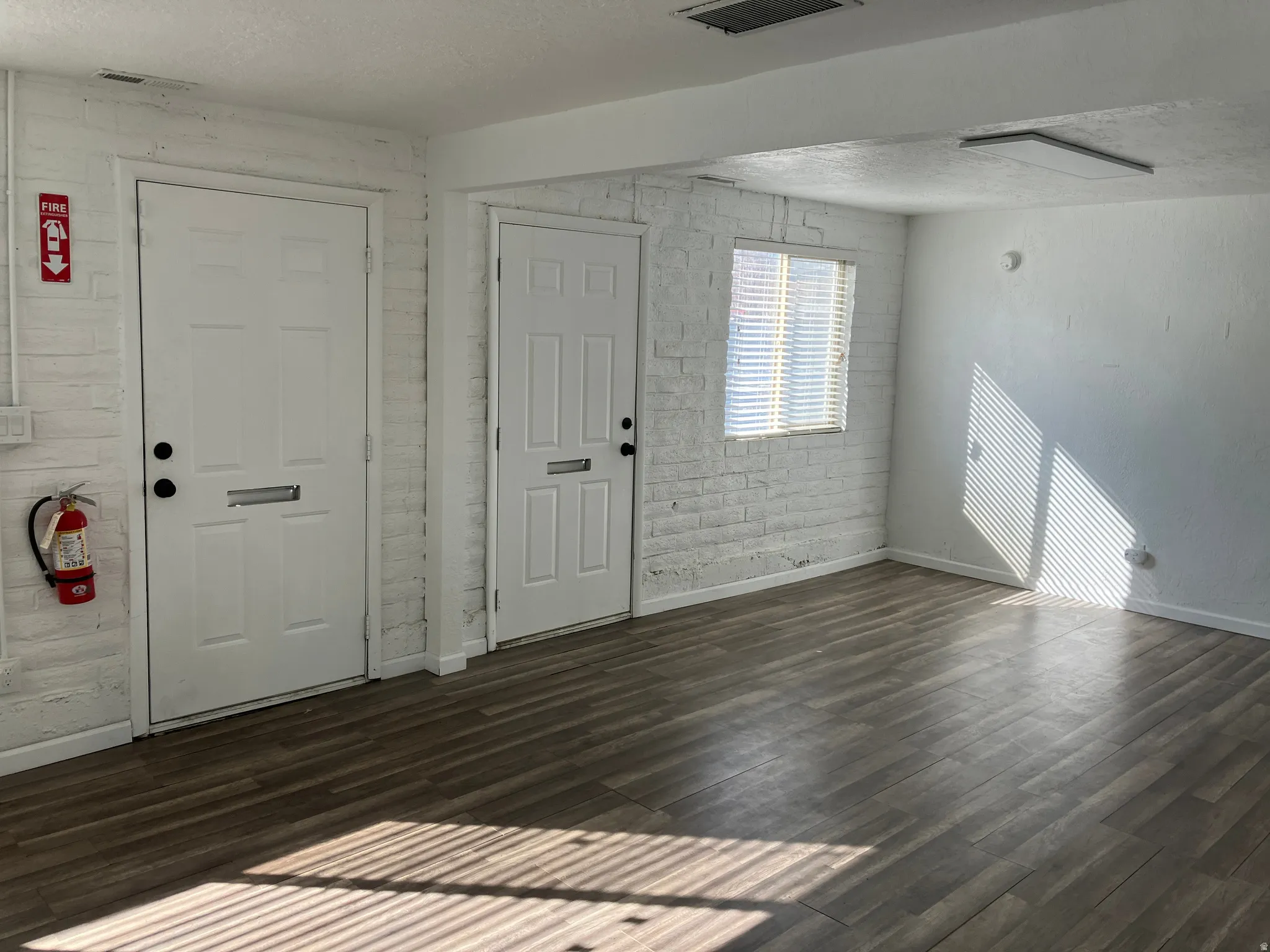 Foyer entrance with a textured ceiling, brick wall, and dark wood finished floors