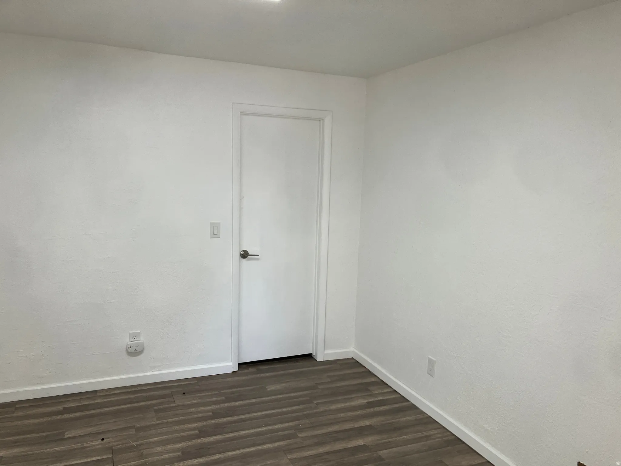 Spare room featuring baseboards and dark wood-style floors
