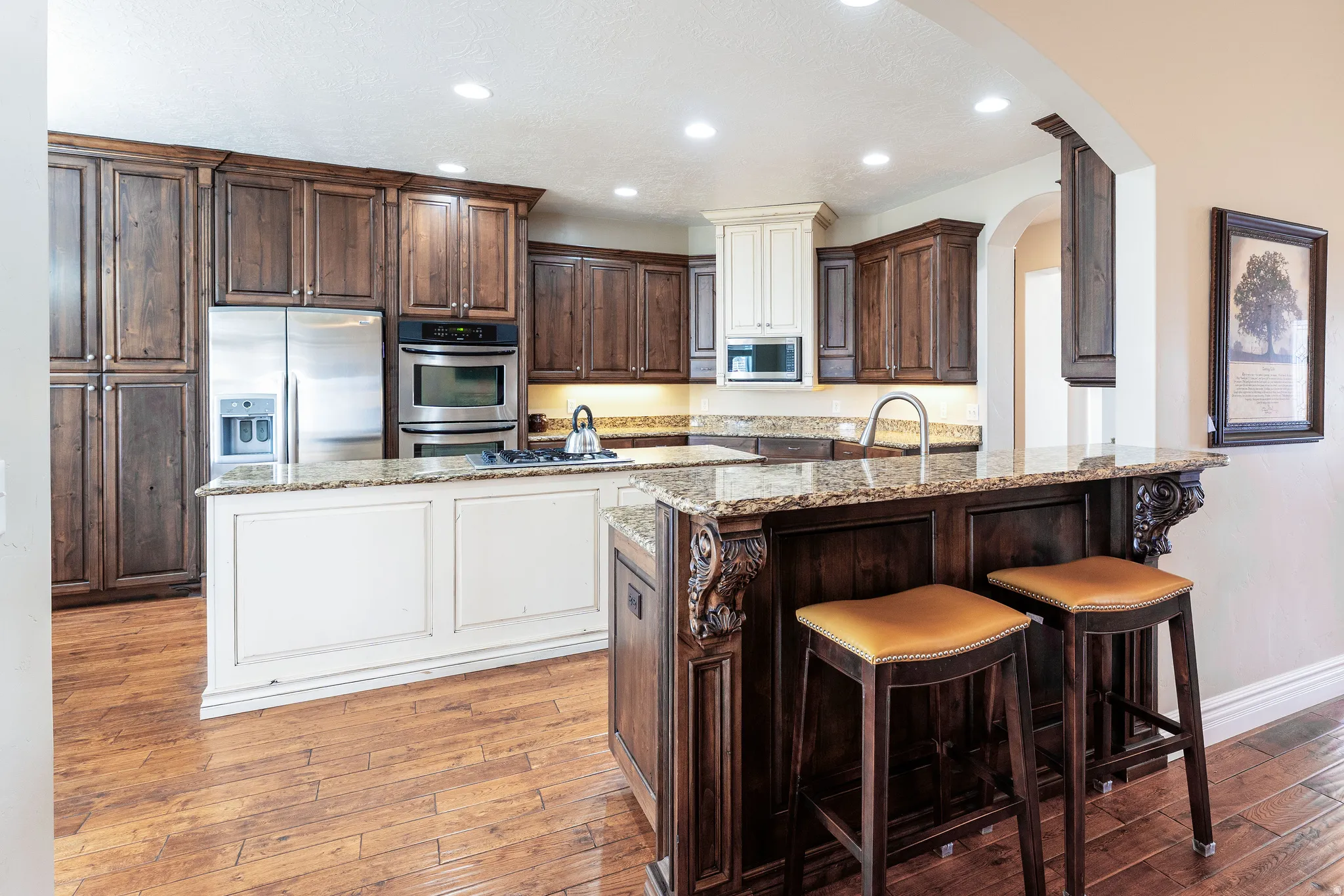 Kitchen featuring two tone cabinetry, light stone countertops, stainless steel appliances, recessed lighting, and light wood-type flooring