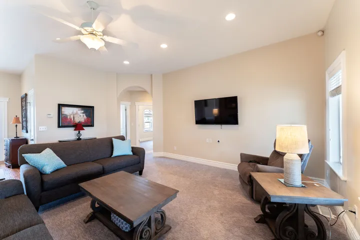 Carpeted living room with a ceiling fan, arched walkways, and recessed lighting