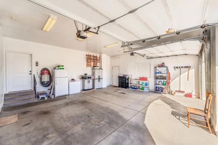 Garage with freestanding refrigerator, white refrigerator, and a garage door opener