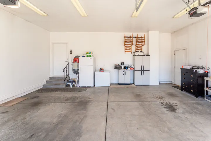 Garage featuring freestanding refrigerator, white refrigerator, and a garage door opener