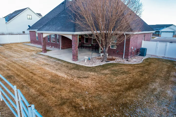 Back of property featuring brick siding, a patio, a shingled roof, and a gate