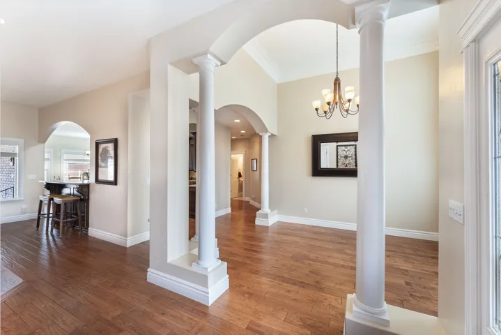 Foyer with dark wood-style floors, arched walkways, and ornamental molding