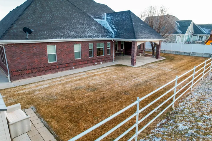 Back of house featuring a patio, roof with shingles, and brick siding