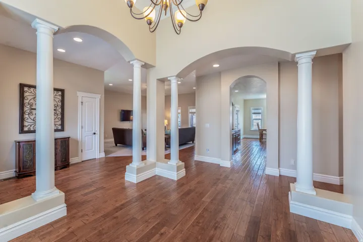 Foyer entrance with decorative columns, arched walkways, dark wood-type flooring, and recessed lighting