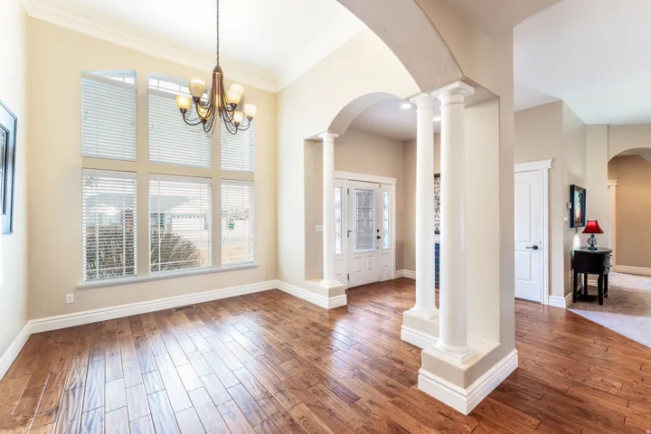 Entrance foyer with arched walkways, decorative columns, hardwood / wood-style floors, ornamental molding, and suspended lighting