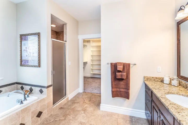 Full bath with a shower stall, a spacious closet, a bath, and vanity