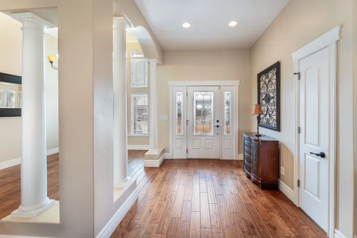 Entrance foyer with ornate columns, dark wood-style flooring, and recessed lighting
