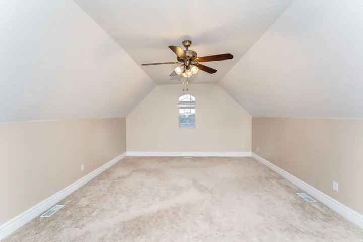 Additional living space with light colored carpet, a ceiling fan, and a textured ceiling